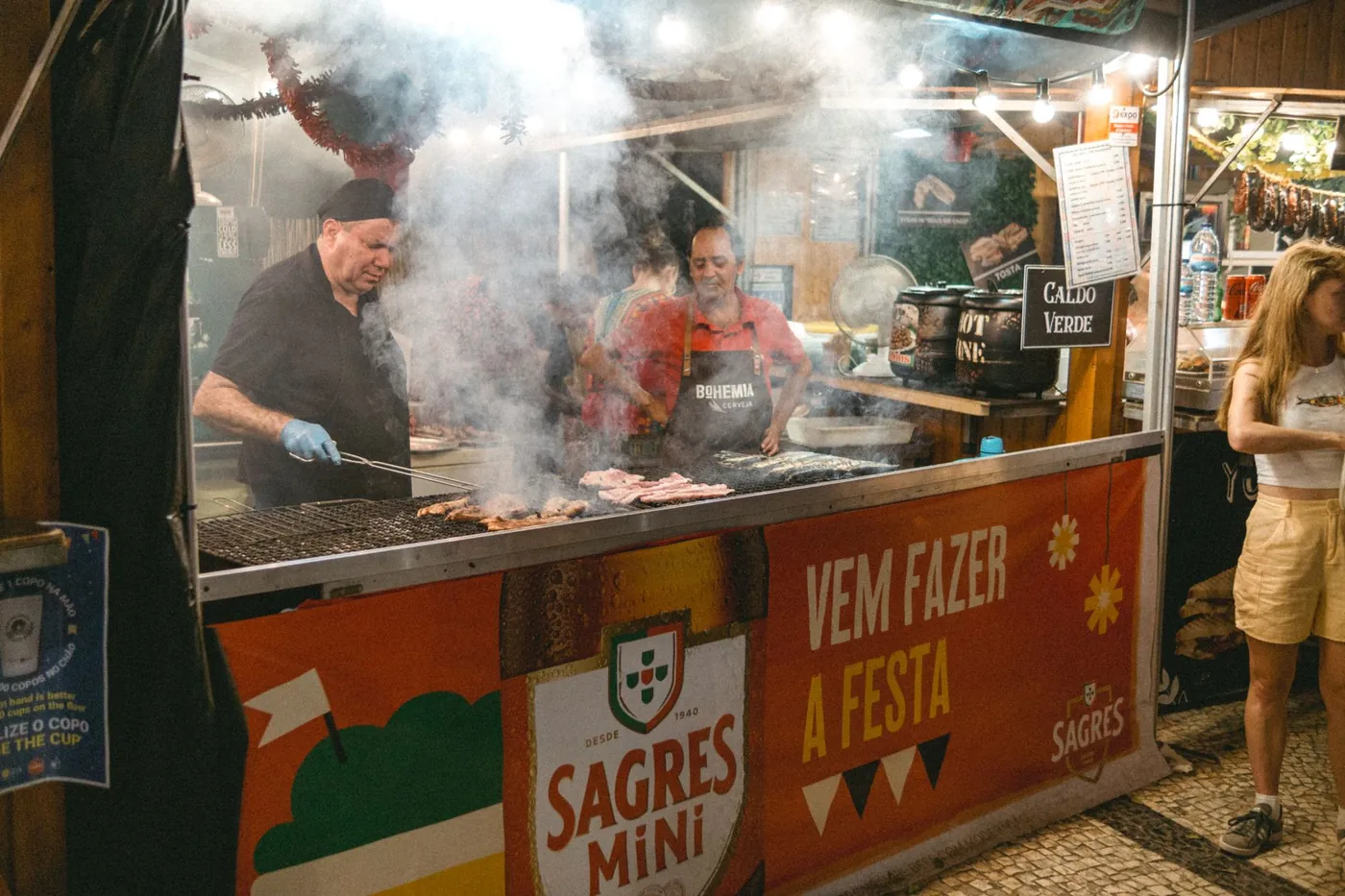Vendors grilling at a street food stall at an evening market in Lisbon, Portugal