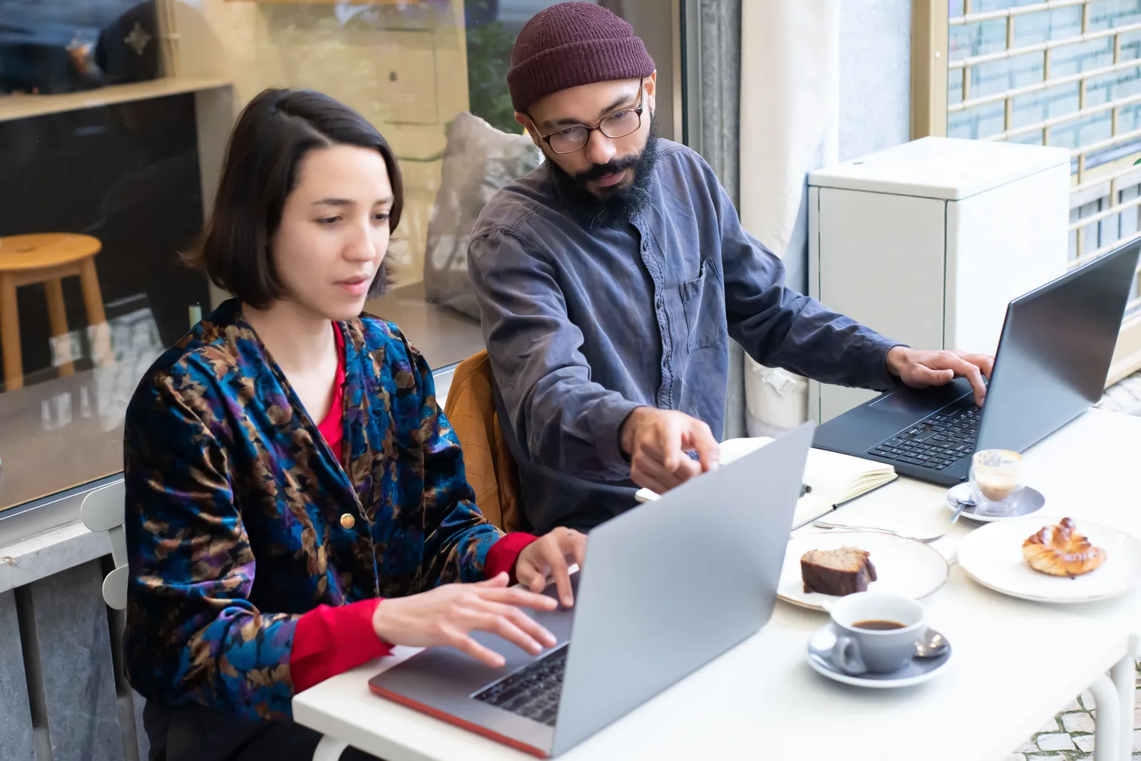 Two people working on laptops at a cafe table in Portugal