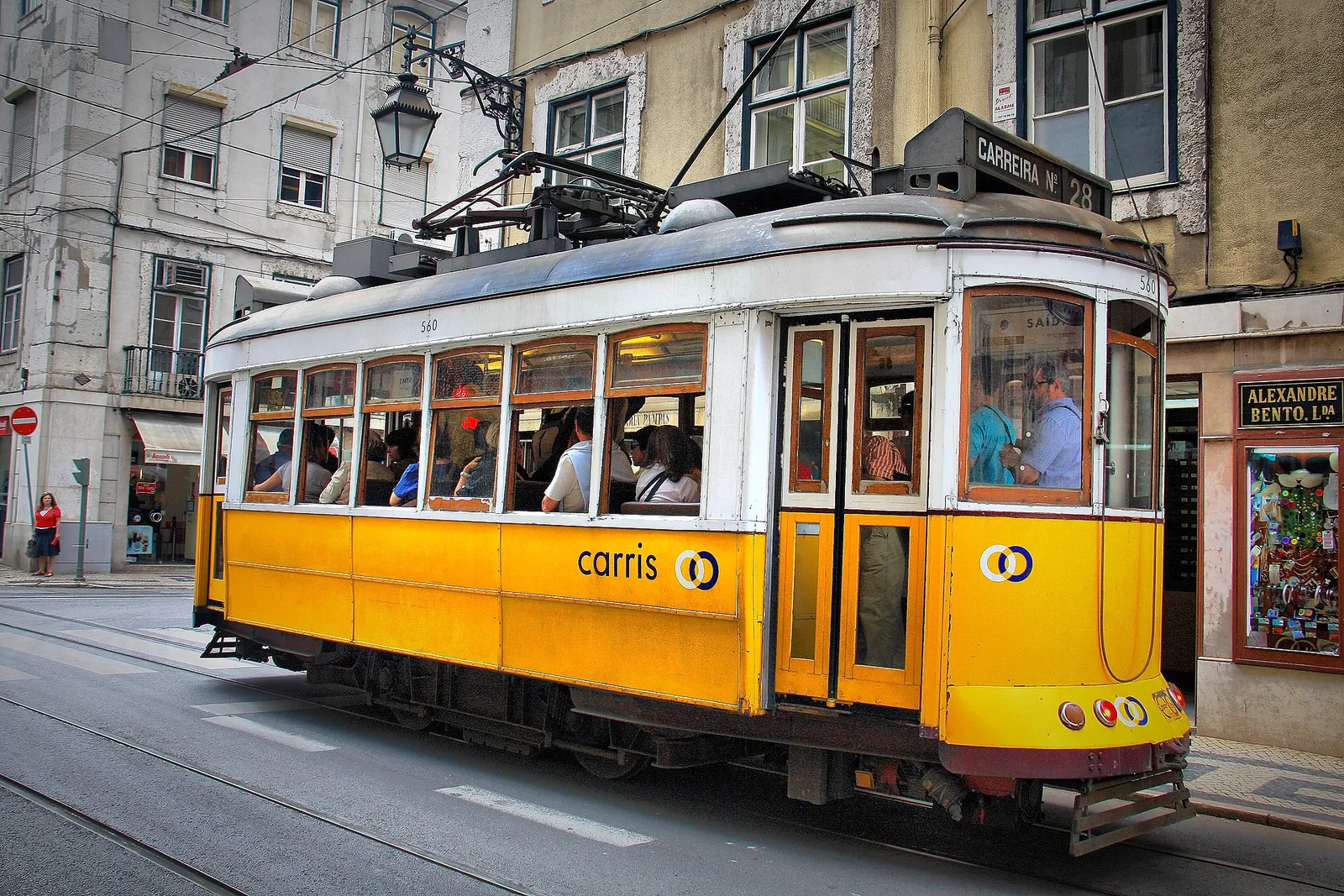 The classic yellow tram 28 climbing a narrow street in the Alfama district of Lisbon, Portugal, on a sunny day