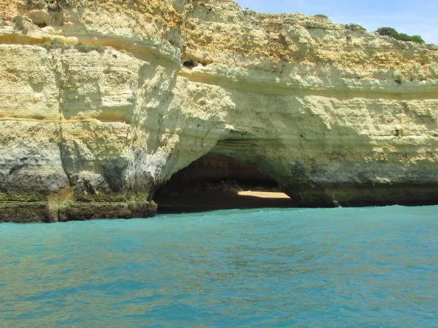 A sea cave in a limestone cliff face above turquoise water