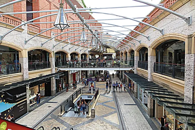 An open two level shopping centre with stone arches and an arched steel canopy