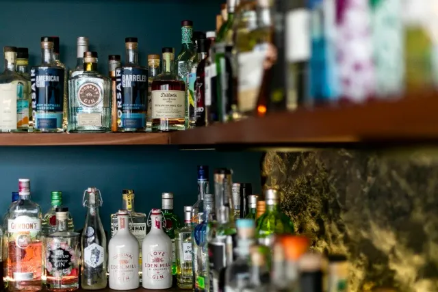 Shelves packed with gin bottles against a teal wall