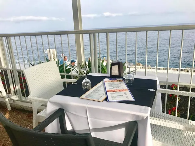 A set table with menus on a white terrace above the ocean