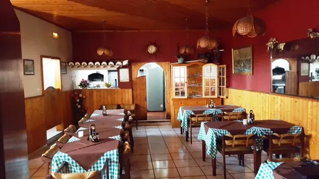 A rustic room with red walls, wood panelling, checked tablecloths and hanging baskets