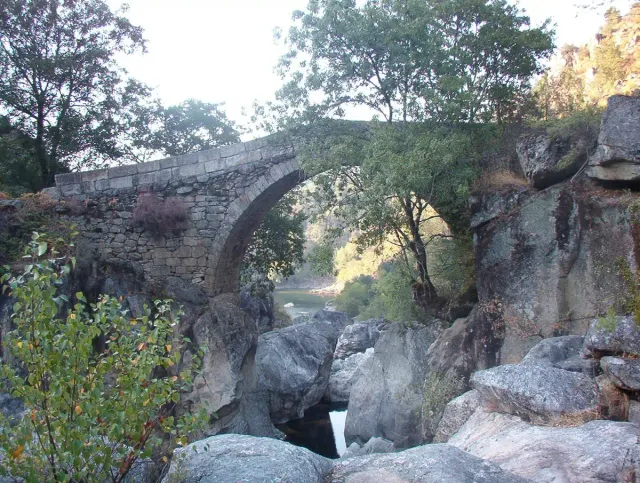 An old stone arch bridge over a narrow rocky gorge
