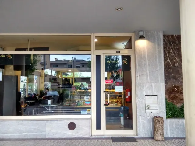 The glass front of a neighborhood cafe with a display case and grey marble walls