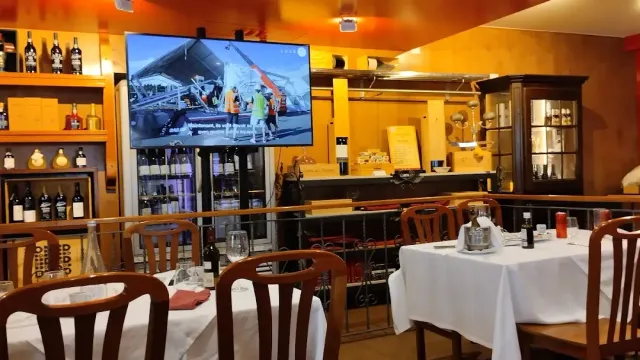 A room with wood panelling, a large screen on the wall and tables in white cloths