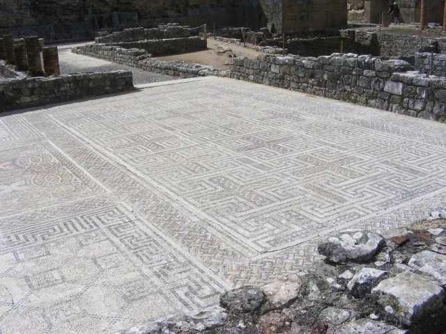 A Roman mosaic floor of geometric patterns between stone walls