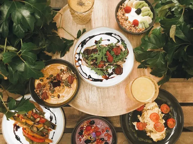 An overhead view of brunch bowls and shakes among green vine leaves