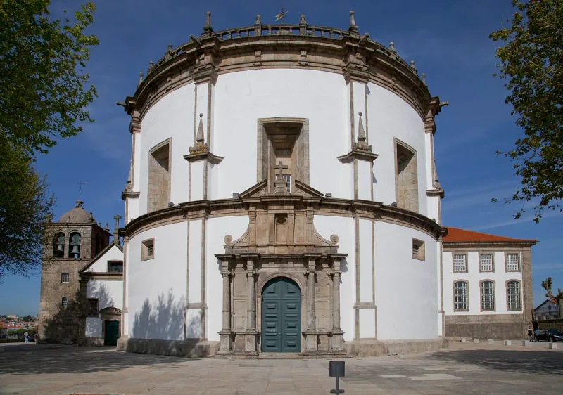 A round white church building with a green wooden door and stone columns around it