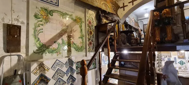 Painted tile panels on a peeling wall, wooden stairs and antique objects