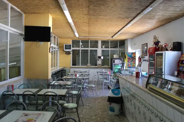 A simple space with formica tables, metal chairs, a chilled counter and a screen on the wall