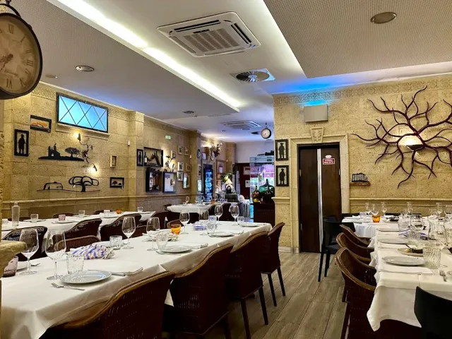 A room with pale stone walls, a large clock and long set tables