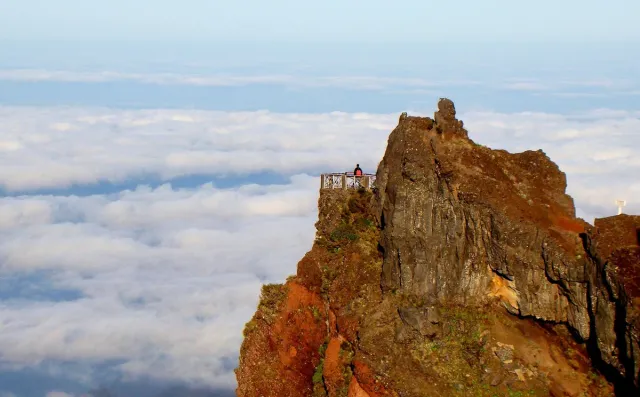 A rocky peak rising above a white blanket of cloud