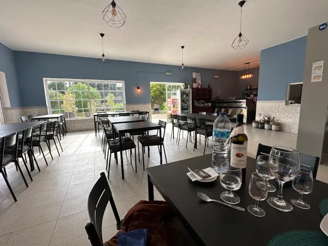 A space with blue walls, black tables, hanging lamps and a counter at the far end