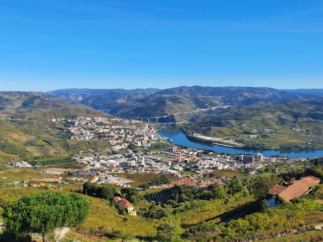 A high view over a white town, a wide river and terraced hills