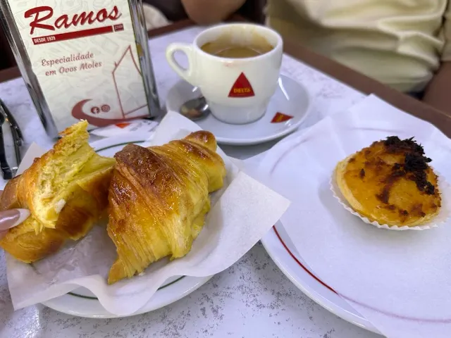 A marble table with a halved pastry, an espresso cup, a small tart and a menu stand