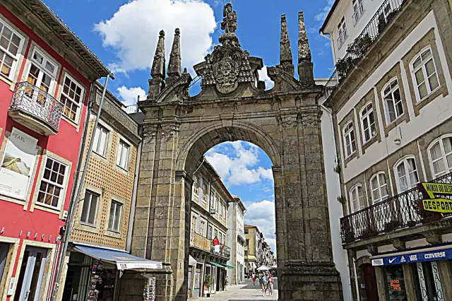 A baroque stone gateway at the end of a street of colourful houses
