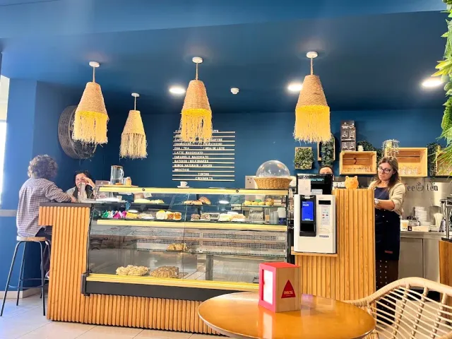 A space with a deep blue wall, yellow fringed lamps and a cake display facing the counter