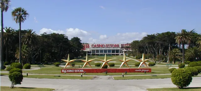 A casino building beyond manicured gardens with gilded star sculptures