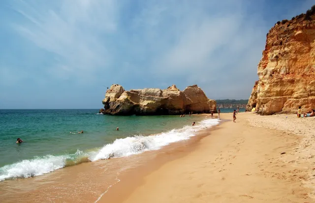 A golden sand beach with rock pillars and orange cliffs