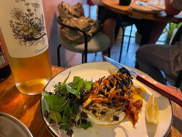 A fish plate with salad leaves and a knife, beside a wine bottle with a floral label