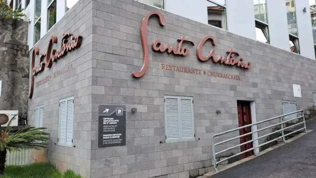 A grey stone clad building with copper letter signage, white shutters and a ramp