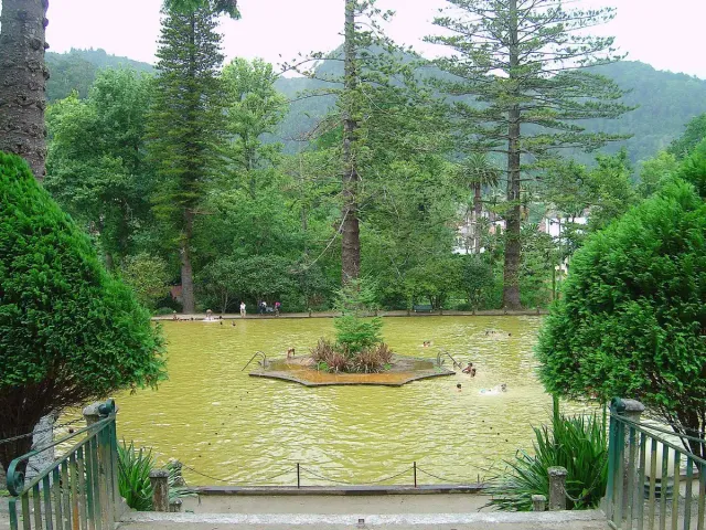 A rust coloured thermal pool with a small tree island at its centre