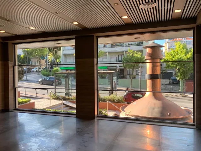 An empty space with a wooden ceiling, wide windows onto the street and a shiny copper vessel