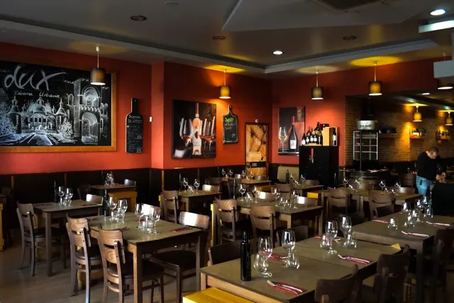 A room with orange walls, a large framed chalk drawing and set wooden tables