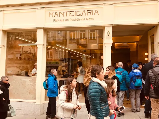 A pale facade with a large sign, a window onto the baking room and a crowd waiting outside