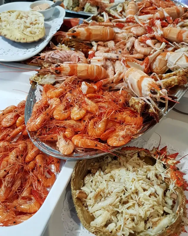 Trays piled with shrimp, langoustines and shredded crab meat on a white surface