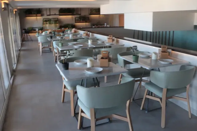 Rows of marble tables and sage green chairs in a modern dining room