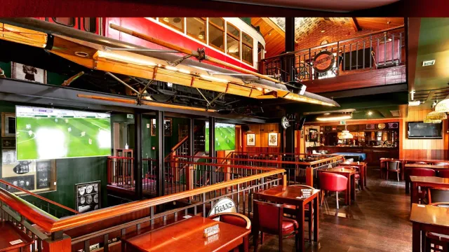 A pub with a rowing boat hung from the ceiling, wooden booths and television screens
