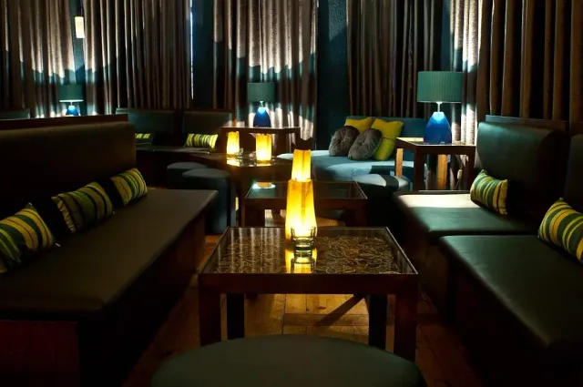 Leather sofas and striped cushions in dim light, orange and blue table lamps