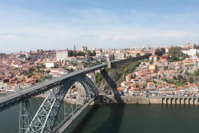 A double deck iron bridge over a river with city rooftops on both banks
