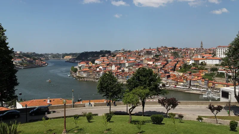 View from a hillside garden over a wide river to an old town of tiled roofs climbing the slope