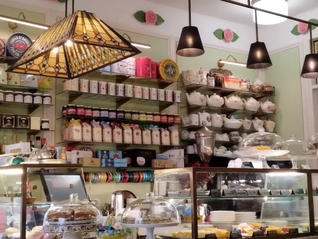 A stained-glass lamp above a counter with glass domes, shelves of tea tins and porcelain teapots