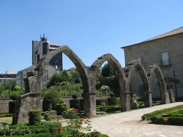 Gothic stone arches of an old palace beside a manicured garden