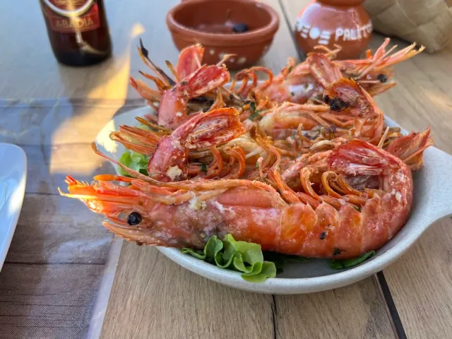 A plate of large red prawns on lettuce leaves beside a beer bottle