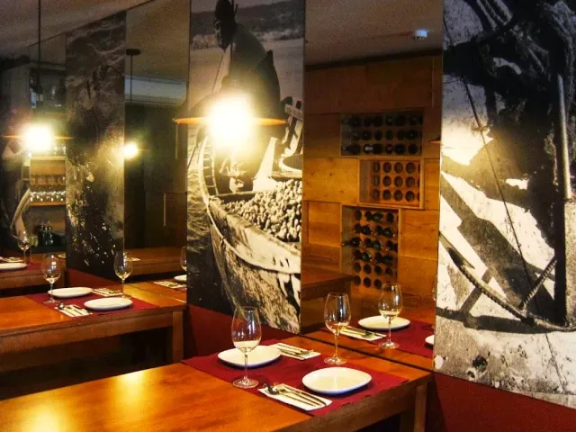 Wooden tables with red cloths between large black and white photographs of fishermen