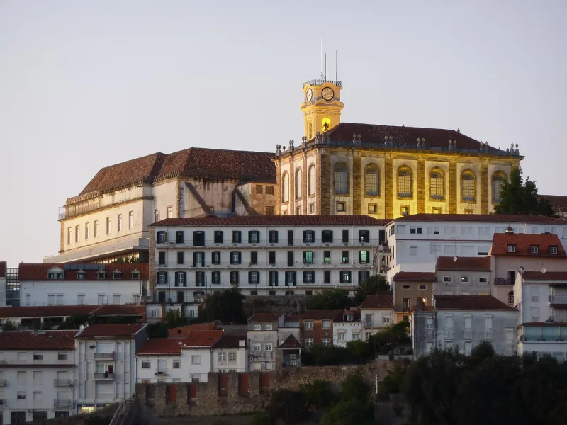 A hilltop university complex with a clock tower above the city rooftops