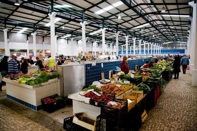 A covered market hall with vegetable stalls and blue tiled counters