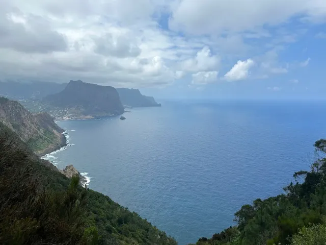 Green cliffs dropping to a grey ocean, with feathery clouds above