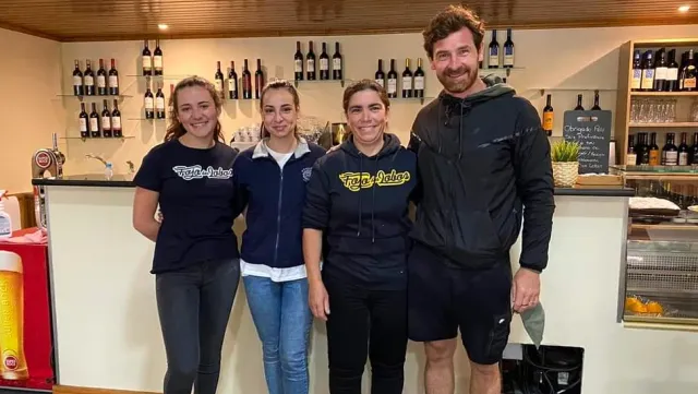 Four people standing in front of a counter with wine bottle shelves on the wall