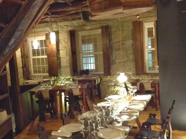 An upper room with stone walls and wooden beams, and a long table set with plates