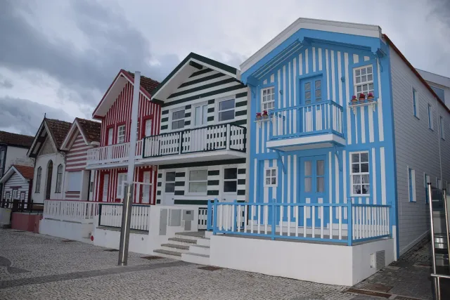 A row of wooden houses in vertical blue, red and green stripes