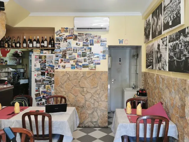 A small space with postcards on the wall, framed photographs, a bottle shelf and a chequered floor