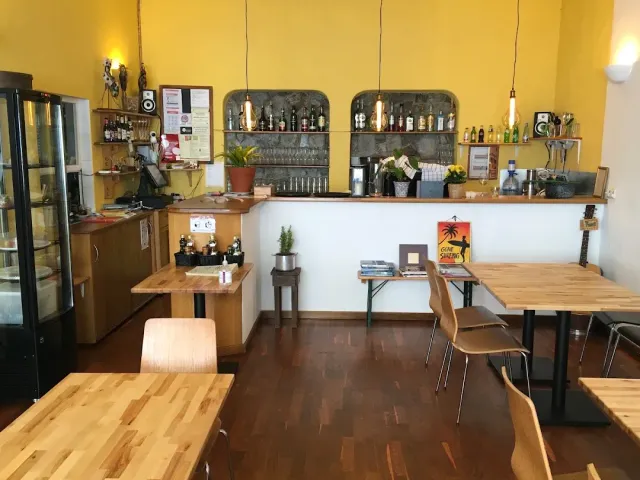 A room with yellow walls, a white counter, bottle shelves and bulbs hanging over wooden tables