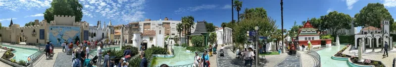 A water pool and miniature buildings among palm trees in a sunlit park